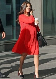 Červené šaty volného střihu pro těhotné v kombinaci s černými botami a černým sáčkem