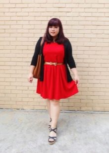 Rode gebreide jurk voor een mollig meisje met een gouden riem, een zwart vest en sandalen