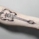 Betekenis en schetsen van een tatoeage in de vorm van een gitaar