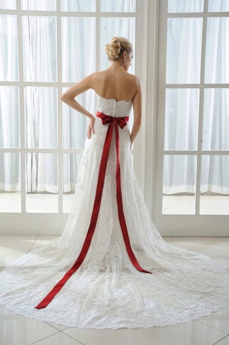 Gaun pengantin dengan busur merah di belakang