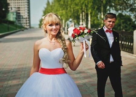 Gaun pengantin dengan selempang merah dan jambangan merah