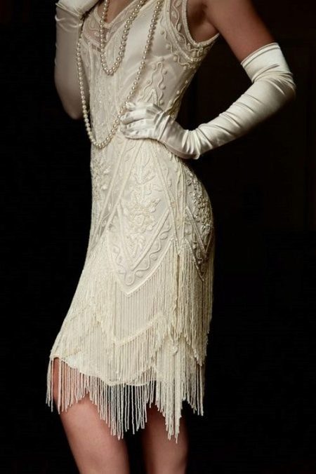 Biele šaty s asymetrickým spodným lemom v štýle Gatsby v kombinácii s rukavicami a perlami