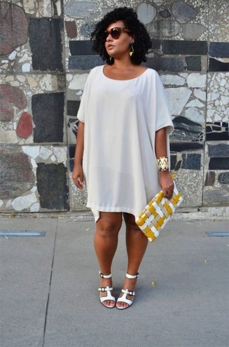 Witte tuniekjurk voor zwaarlijvige vrouwen in combinatie met witte sandalen en gouden accessoires